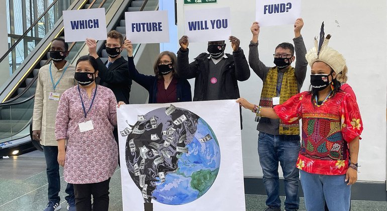 A group armed with signs pose for photographers at the main corridor of the Blue Zone at the COP26 Climate Conference in Glasgow, Scotland.