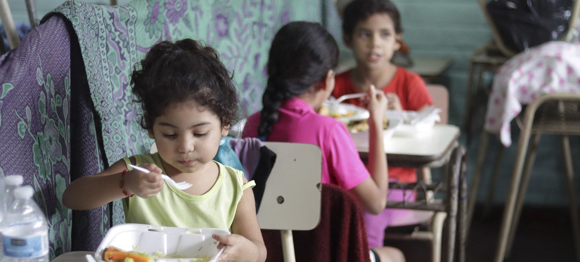 在萨尔瓦多，一所学校已经变成临时收容所，世界粮食计划署工作人员在该收容所中向新冠病毒大流行中失去生计的家庭分发粮食。