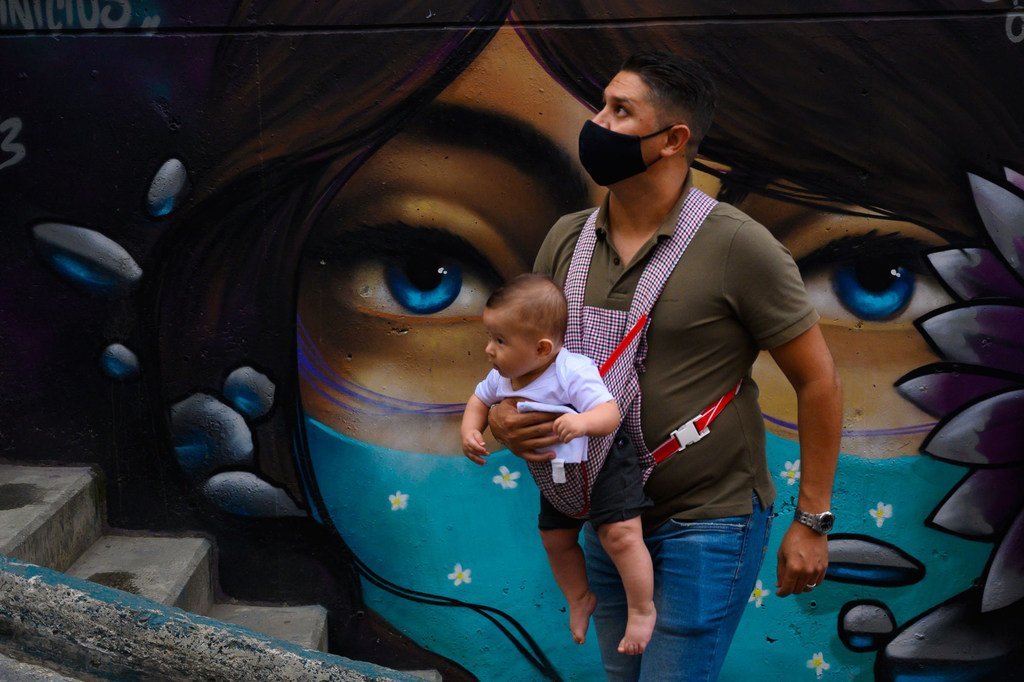 un homme portant un masque et son enfant dans le quartier Comuna 13 à Medellin, la capitale de la Colombie.