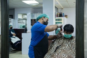 पाकिस्तान के कराची शहर में एक नाई मास्क पहनकर ग्राहक के बाल काट रहा है. 