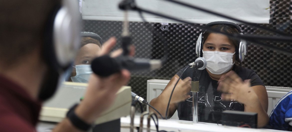 Crianças em Espanha fazendo programa de rádio que serve uma comunidade de Sevilha