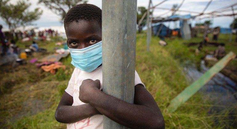 मोज़ाम्बीक़ में तूफ़ान द्वारा अपने घर तबाह होने के बाद, अनेक परिवारों को एक अस्थाई आवास स्थल में ठहराया गया. एक बच्चा फ़ेस मास्क पहने हुए.