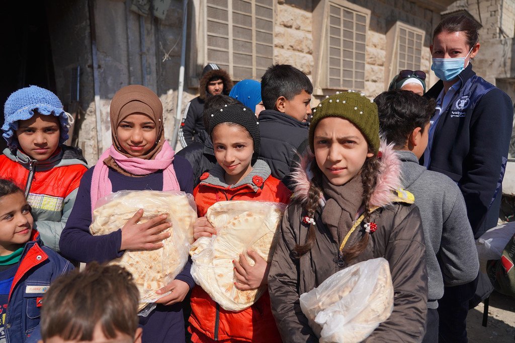 这些儿童从叙利亚阿勒颇的一家面包店领取面包，世界粮食计划署正在那里协助分发粮食。