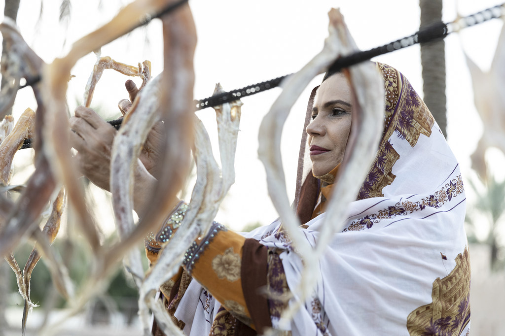 3 أكتوبر 2021، السيب، عُمان - امرأة ساحلية تُعلق أسماك القرش المجففة، المعروفة محليا باسم أوال، حتى تجف.