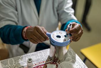 一名医务人员将用过的新冠疫苗注射器丢弃在一个容器中。