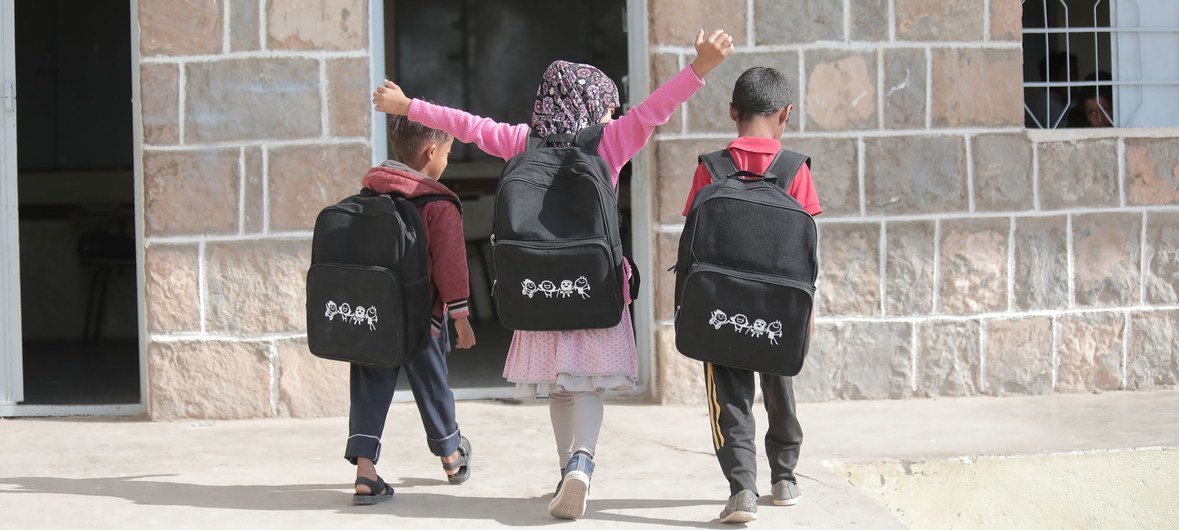 أطفال صغار يسيرون في تعز المتضررة بسبب الصراع في اليمن وقد حصلوا على حقائب مدرسية جديدة في كانون الثاني-يناير 2020