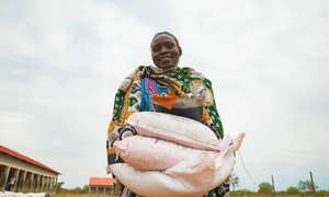 A woman carries sacks of seeds distributed to families in South Sudan during the COVID-19 pandemic.