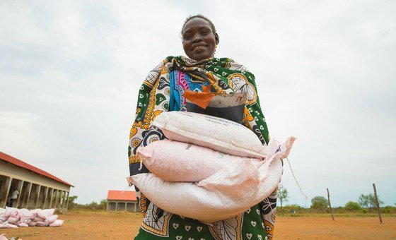 Mulher do Sudão do Sul carrega suprimentos distribuídos a famílias em necessidade durante pandemia