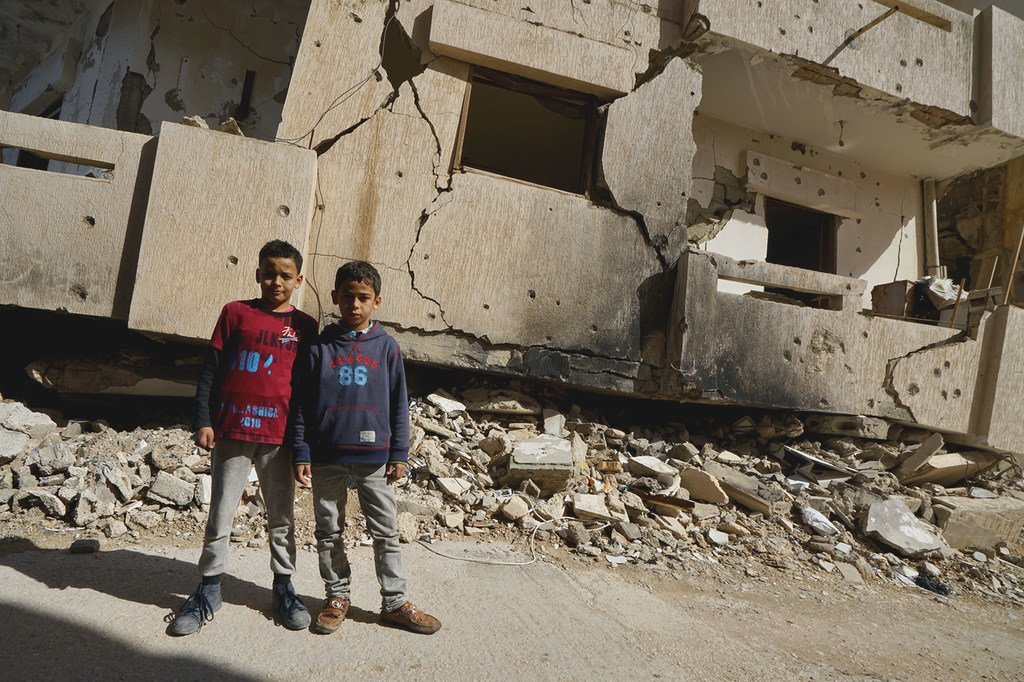 De jeunes garçons se tiennent devant un bâtiment détruit à Benghazi, en Libye (photo d'archives).