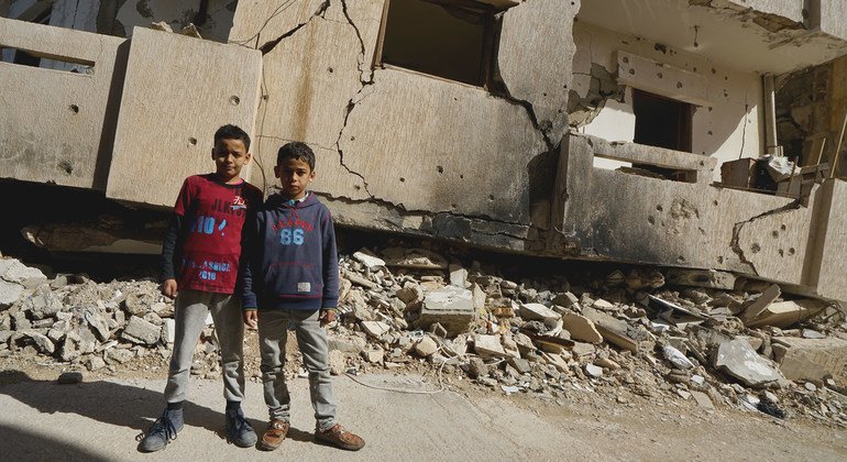 طفلان يقفان أمام مبنى مدمر في بنغازي (من الأرشيف)