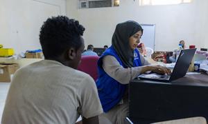 An IOM staff member registers an Ethiopian migrant in Ma’rib, Yemen, prior to travel to Addis Ababa.