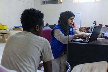 An IOM staff member registers an Ethiopian migrant in Ma’rib, Yemen, prior to travel to Addis Ababa.