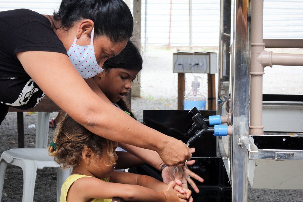 一名妇女和儿童使用联合国儿童基金会在巴西北部博阿维斯塔的一个非正式城镇安布拉特尔安装的新洗手设施。