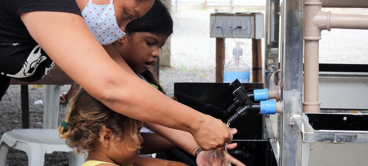 A woman and children use new handwashing facilities installed by UNICEF in Embratel, an informal urban settlement in Boa Vista, in northern Brazil.