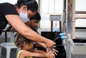 一名妇女和儿童使用联合国儿童基金会在巴西北部博阿维斯塔的一个非正式城镇安布拉特尔安装的新洗手设施。