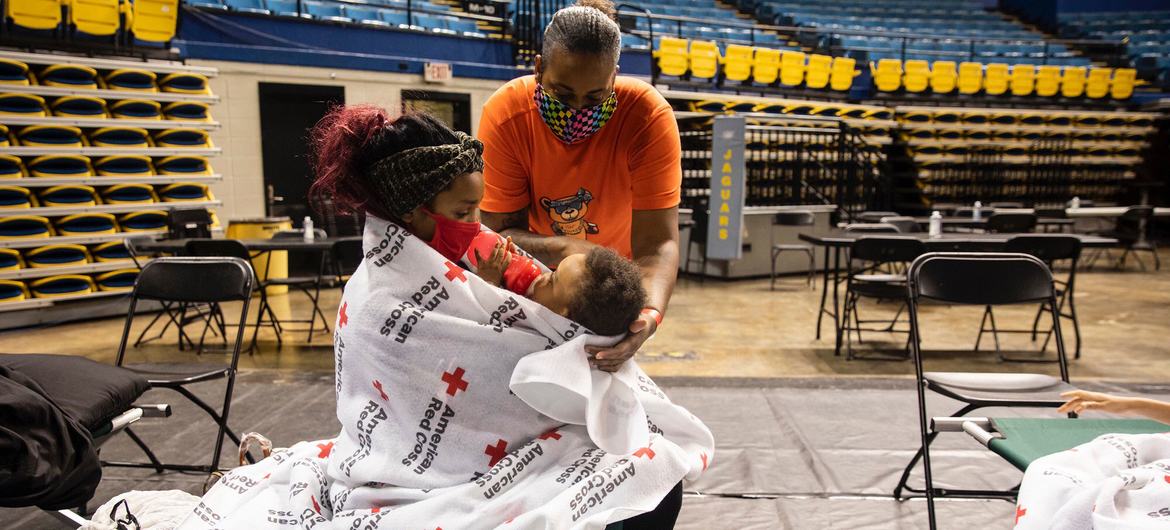 A teenage girl provides comfort to her baby brother at a Red Cross evacuation shelter after Hurricane Ada hit Louisiana in August 2021.