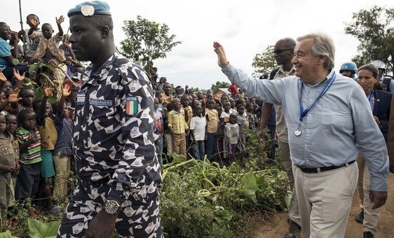 Secretary-General António Guterres is accompanied by a peacekeeper from the UN Organization Stabilization Mission in the Democratic Republic of the Congo (MONUSCO) as he waves to a local community while visiting Mangin, in the Ebola-stricken part of North