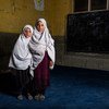 在阿富汗楠格哈尔省的学校里，两个在简易爆炸装置袭击中失去兄弟的姐妹摆好姿势拍照。
