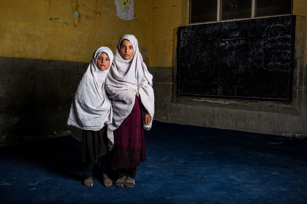 在阿富汗楠格哈尔省的学校里，两个在简易爆炸装置袭击中失去兄弟的姐妹摆好姿势拍照。