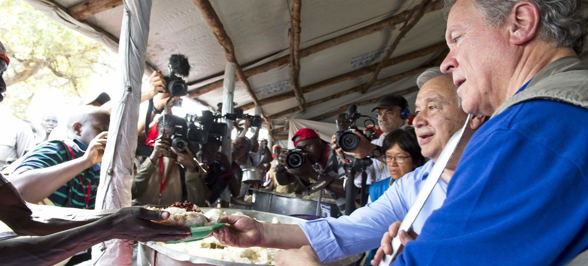 El Secretario General de la ONU, António Guterres (segundo de derecha a izquierda), y el director ejecutivo del PMA David Beasley, sirven alimentos en la zona de recepción de refugiados en el campamento Imvepi.