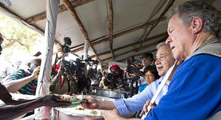 El Secretario General de la ONU, António Guterres (segundo de derecha a izquierda), y el director ejecutivo del PMA David Beasley, sirven alimentos en la zona de recepción de refugiados en el campamento Imvepi.
