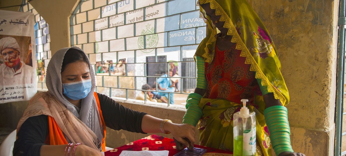 一名妇女在巴基斯坦受洪灾影响的家庭食品分发点登记领取世界粮食计划署发放的口粮。