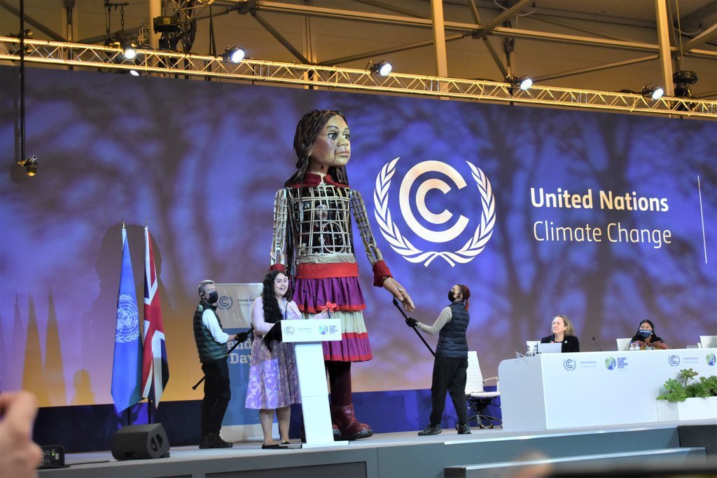 الناشطة المناخية بريانا فروين من ساموا تشارك المنصة مع دمية عملاقة تجسد فتاة سورية لاجئة.