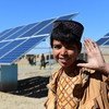 A boy waves in front of solar panels that provide electricity to pump water, in Herat, western Afghanistan. 
