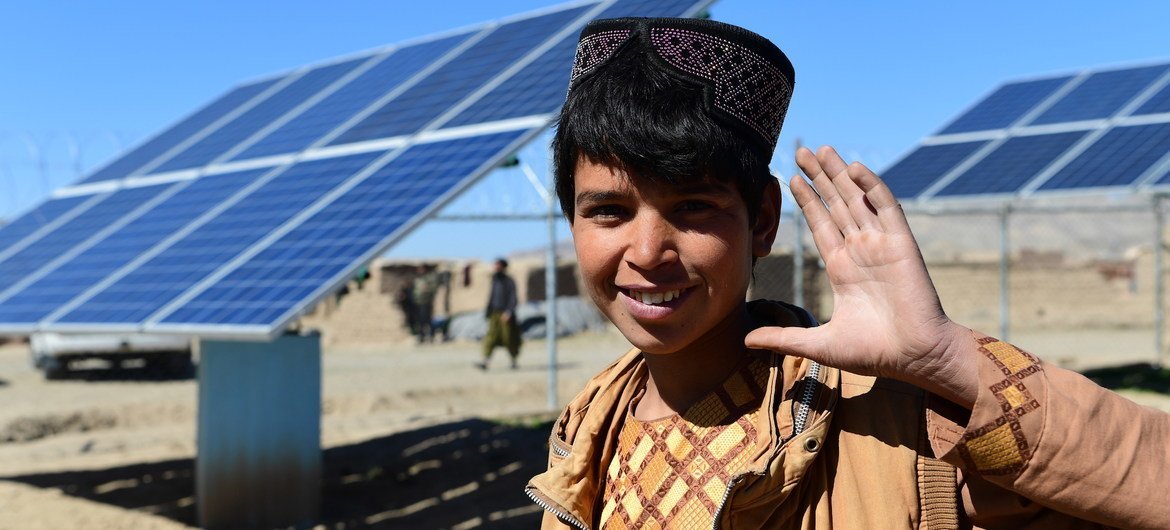 Un joven posa en frente de paneles solares que proveen energía para transportar agua en Herat, Afganistán.