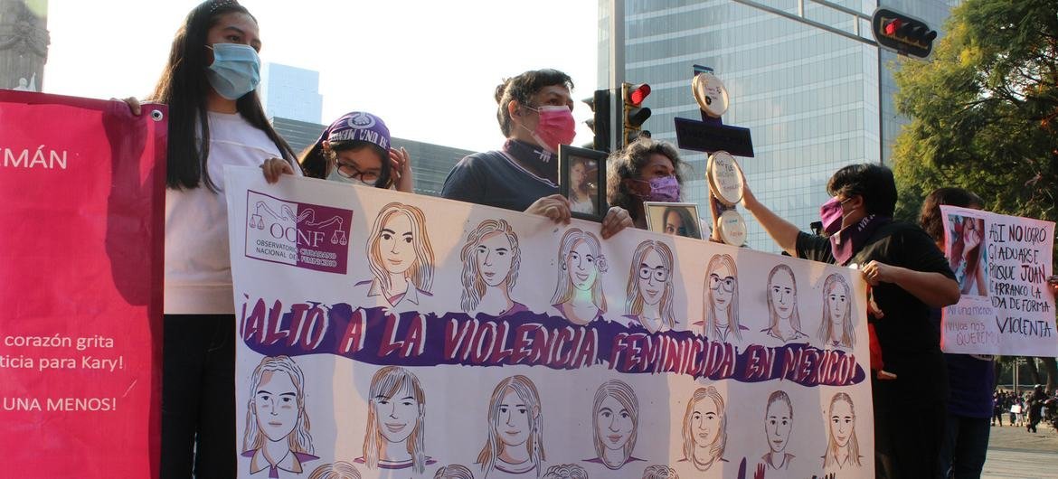 Un grupo de personas sostiene una pancarta con retratos de mujeres durante una protesta contra el feminicidio en México.