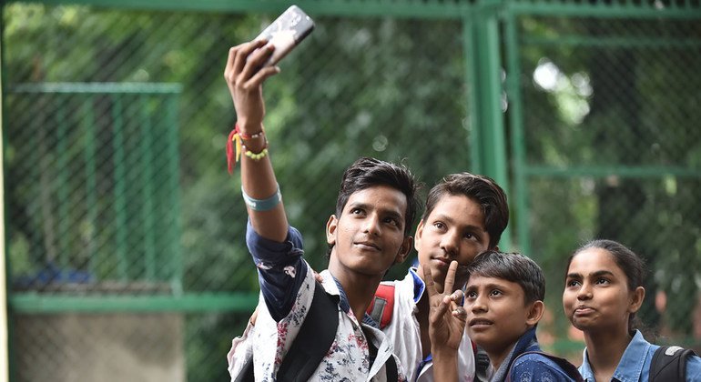 A boy uses his mobile phone to take a selfie with his friends at a school in New Delhi, India.
