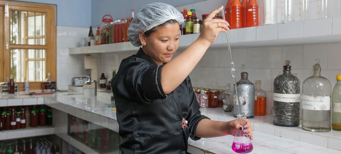 A female trainee chemist conducts a test at a fruit company in Samtse, Bhutan.