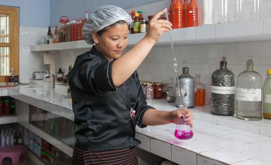 A female chemist conducts an experiment at a fruit company in Samtse, Bhutan.