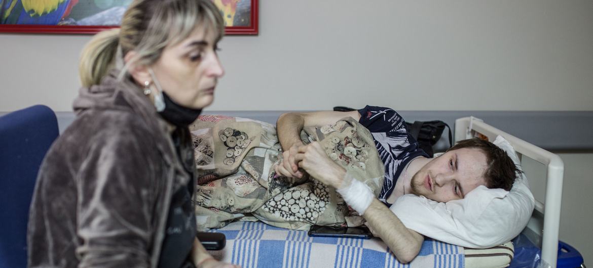 On 3 March 2022, a woman sits beside the stretcher of her son, who has been receiving treatment for three weeks at a hospital in Kyiv, Ukraine.