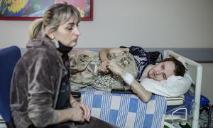 Une femme assise à côté de son fils qui est soigné dans un hôpital à Kyïv, en Ukraine (3 mars 2022).