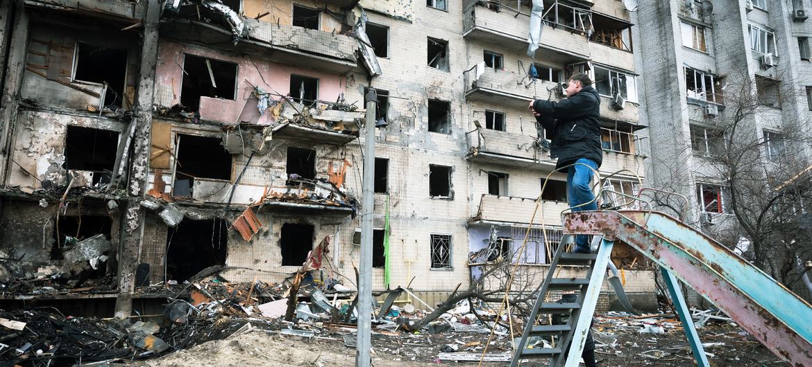 Мужчина фотографирует сильно поврежденный в результате обстрелов многоквартирный дом в Киеве, Украина.