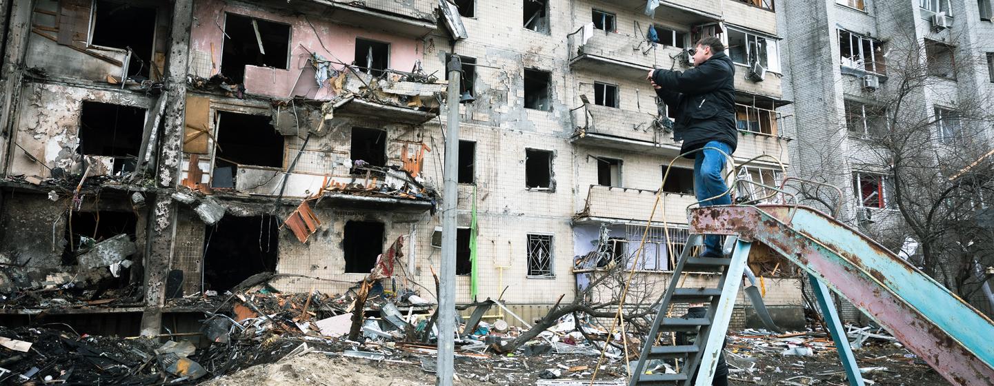 A man photographs an apartment building that was heavily damaged during escalating conflict, in Kyiv, Ukraine.