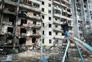 Un homme photographie un immeuble d'habitation qui a été fortement endommagé lors de l'escalade du conflit, à Kyïv, en Ukraine.
