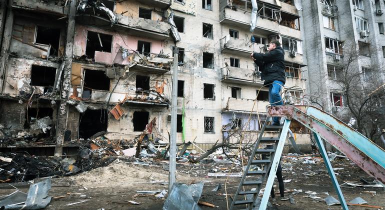 رجل يصور مبنى سكنيًا تعرض لأضرار جسيمة أثناء الصراع المتصاعد ، في كييف ، أوكرانيا.