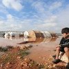 2021年1月19日，叙利亚西北部伊德利卜，一名流离失所的男童望着遭洪水淹没的营地。