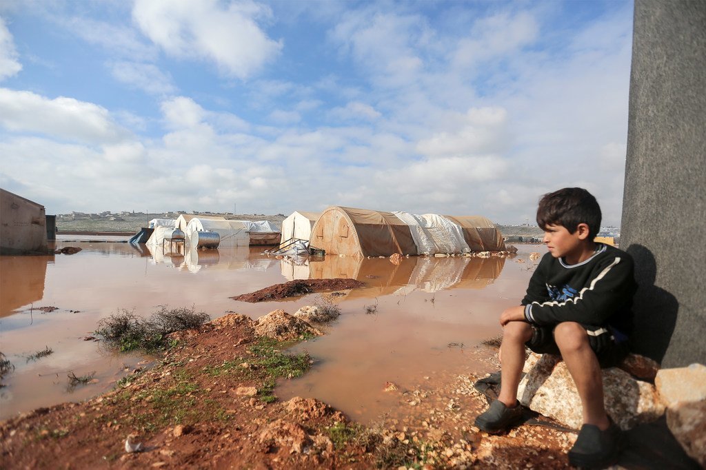 في 19 كانون الثاني/يناير، طفل ينظر إلى مخيم كفر لوسين في شمال غرب سوريا الذي تعرّض لفيضانات.