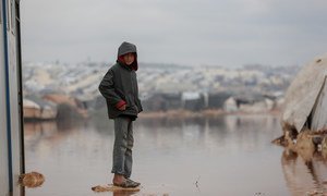 A child is surrounded by floodwater in Kafr Losin Camp in northwestern Syrian.