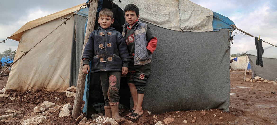 أطفال نزحوا على عائلاتهم بسبب الحرب في سوريا، يقفون خارج خيمتهم في شمال البلاد.