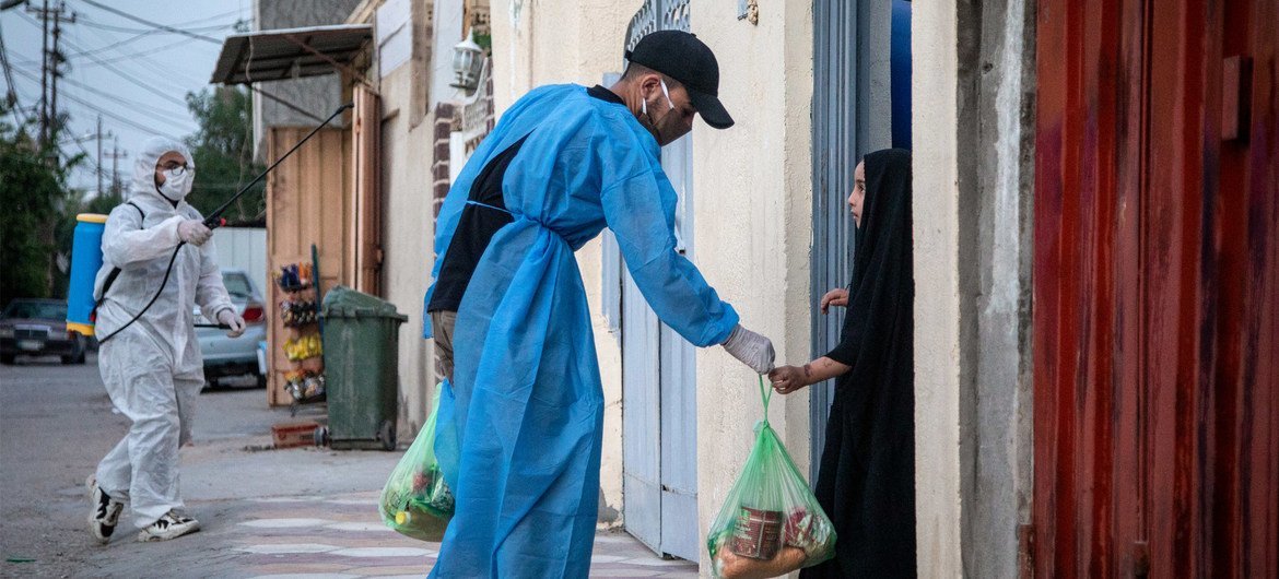 أحد المتطوعين يقدم الطعام لطفلة في كربلاء بالعراق بعد فرض حظر التجول بسبب فيروس كورونا.