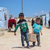 Brothers Ahmad (left), 7, and Saad, 5, carry a hygiene kit back to their tent in Fafin camp, northern rural Aleppo.