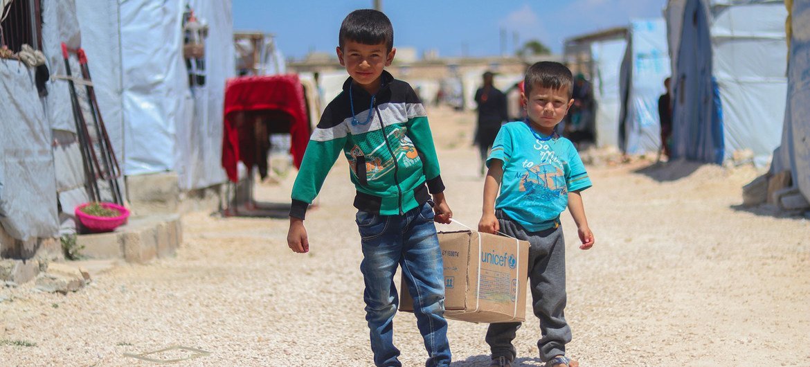 Brothers Ahmad (left), 7, and Saad, 5, carry a hygiene kit back to their tent in Fafin camp, northern rural Aleppo.
