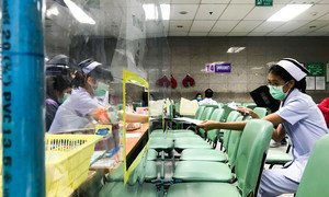 Nurses at a hospital in Bangkok, Thailand, exchange documents through acrylic shields that have been setup to ensure physical distancing. 