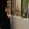 在国际家政工人日，卡塔尔一名妇女在休假时观看家政工人肖像展览。