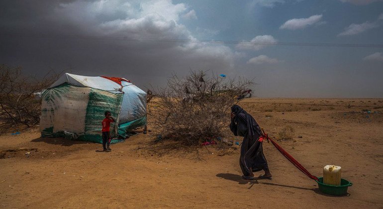 Idosa leva água para sua tenda em um campo de deslocados no norte do Iêmen, perto da fronteira com a Arábia Saudita 