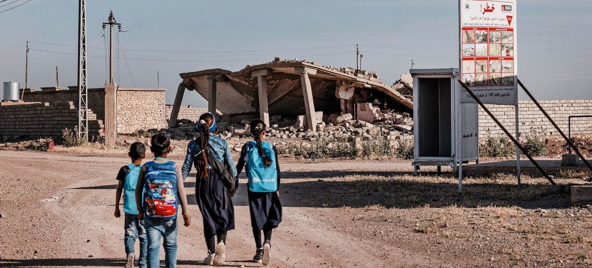 Crianças no Iraque passam por zona com aviso que alerta para a presença de minas terrestres. 